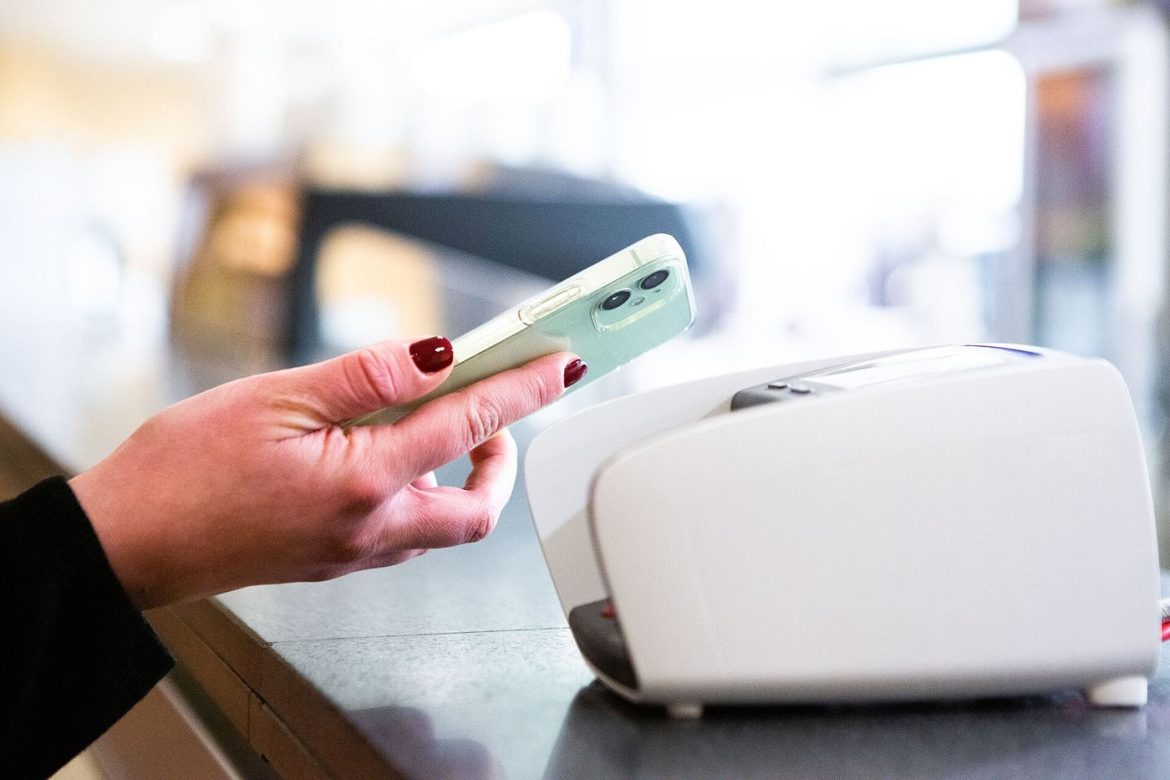 A traveller paying with a smartphone at a payment terminal